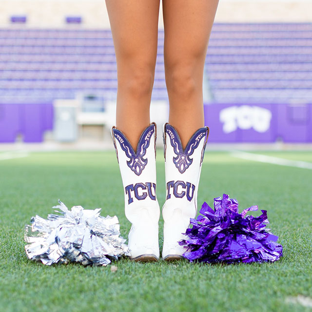 Las piernas de una corista de la TCU con sus botas posando para mostrar sus botas TCU personalizadas blancas y moradas.